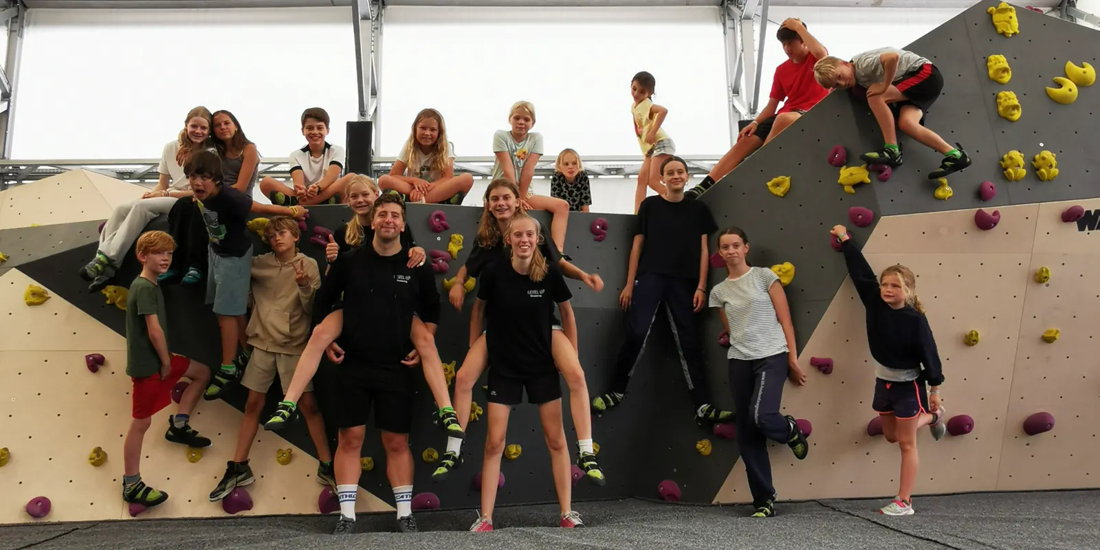 Een groep kinderen en begeleiders op de boulderwand
