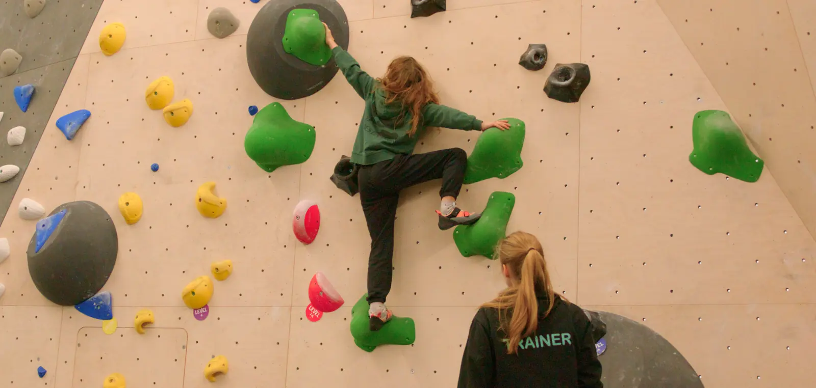 Kinderen met begeleiders bovenop een boulderblok