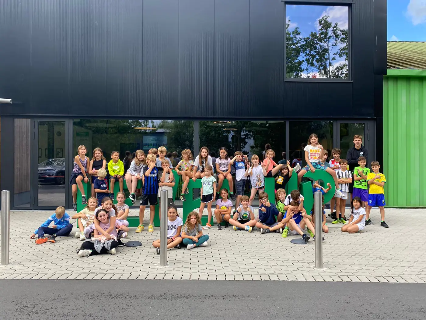 Kinderen poseren bij de grote groene letters van Level Up