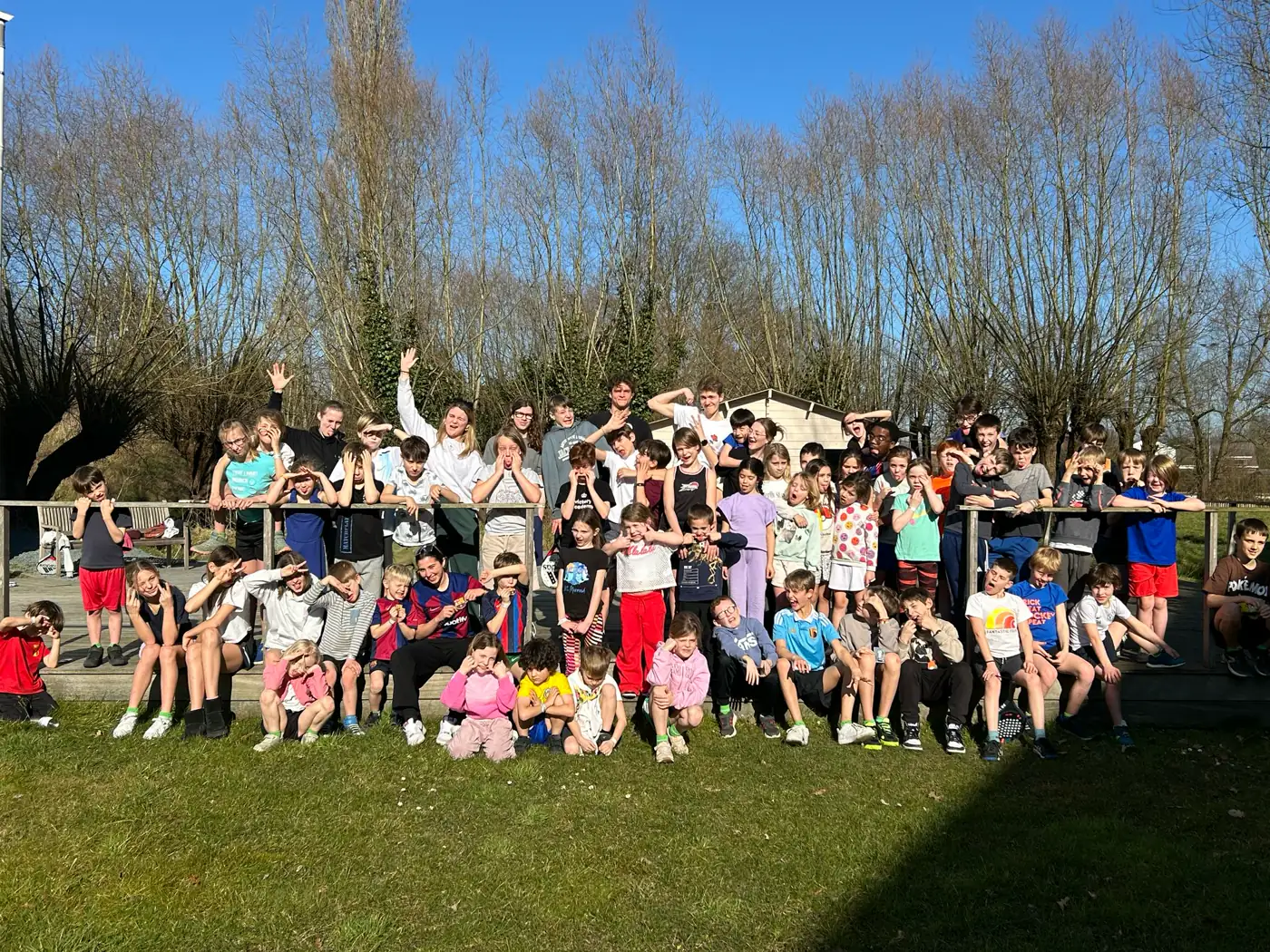 Een groep kinderen en begeleiders poseert buiten in de zon