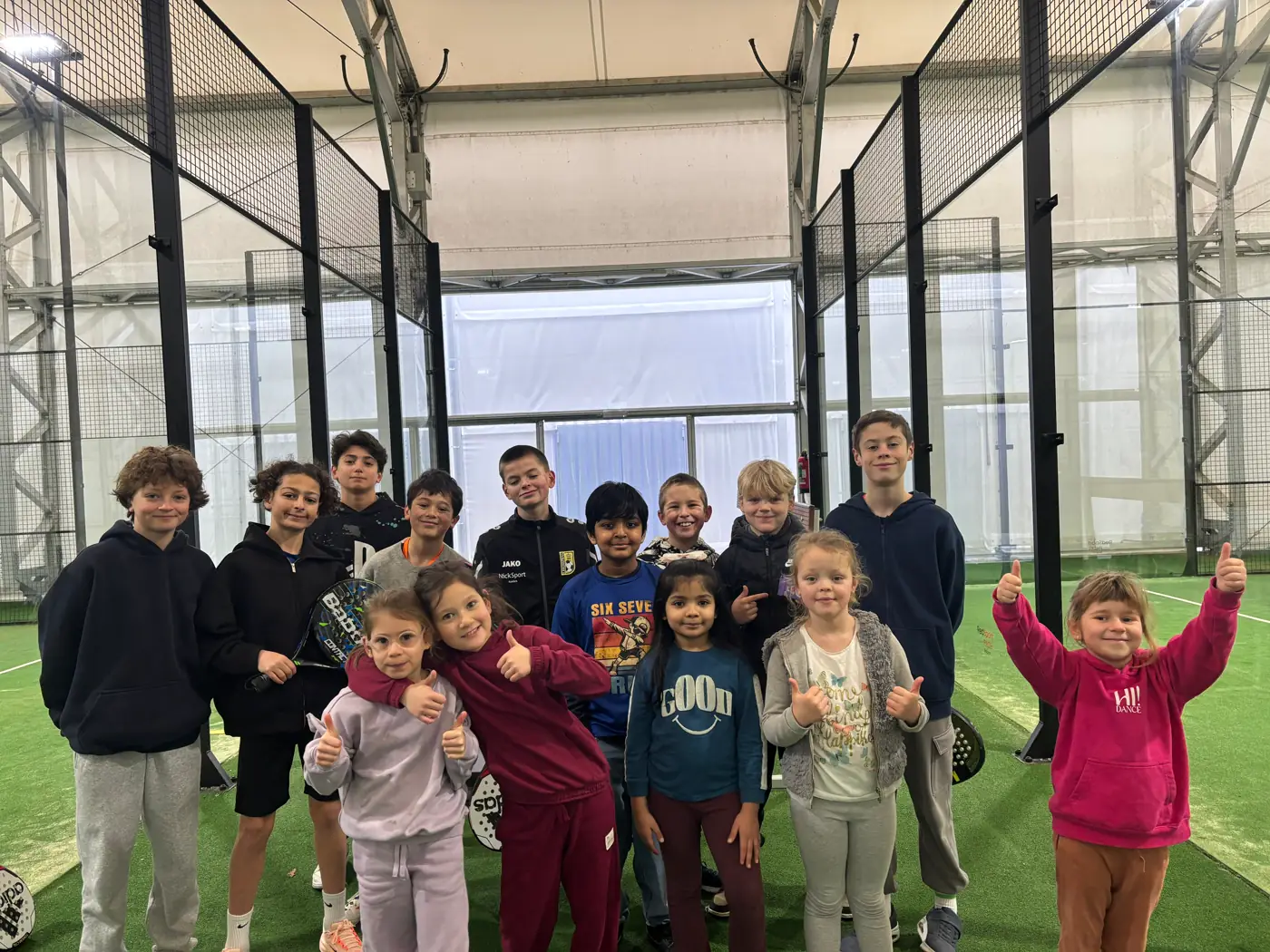 Kinderen met duimen omhoog op het padelveld